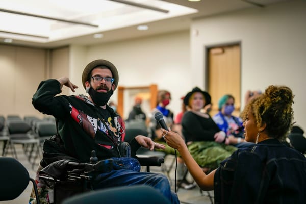 A man using a wheelchair speaks to a crowd