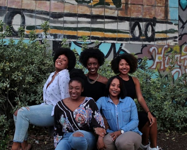 A group of women sit in front of a garden wall