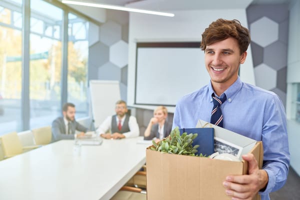A man carrying a box smiles while exiting his offboarding meeting